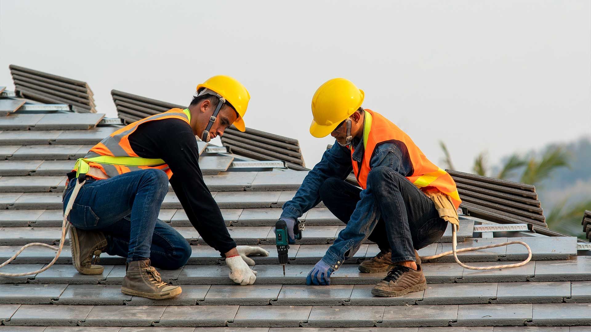 Two construction workers are working on a roof.